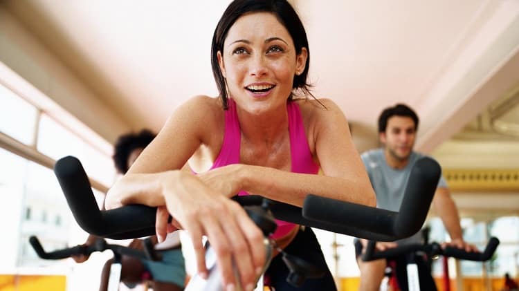 Group Of People Sitting On Exercise Bikes